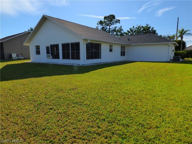 back of property featuring central AC and a yard