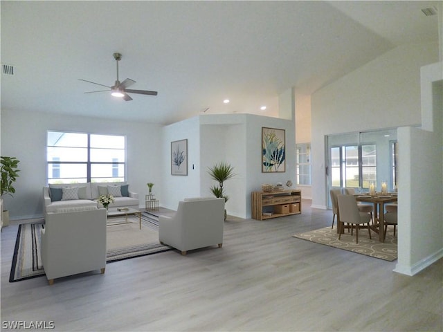 living room with lofted ceiling, ceiling fan, and light hardwood / wood-style flooring