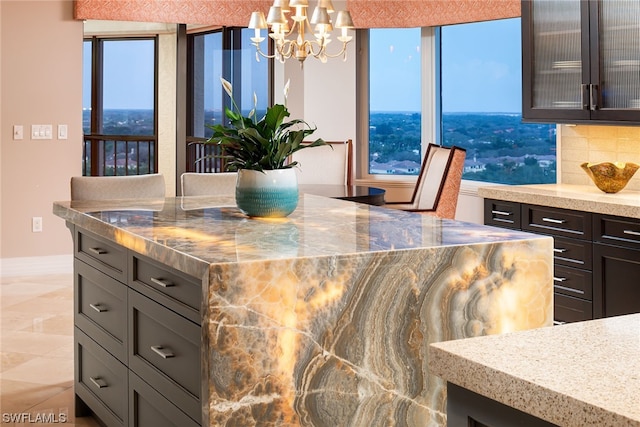 kitchen featuring a notable chandelier, decorative light fixtures, tasteful backsplash, and light stone countertops