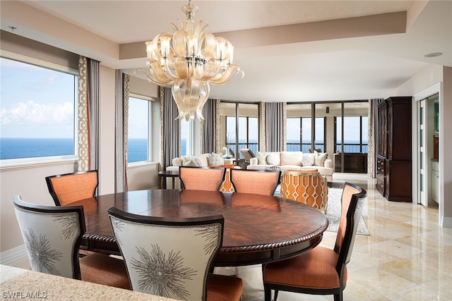 dining room with light tile floors, a chandelier, and a water view