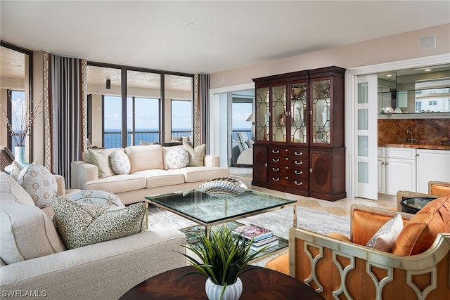 tiled living room with a water view and sink