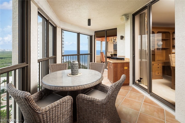 sunroom / solarium featuring a water view, an inviting chandelier, and a wealth of natural light