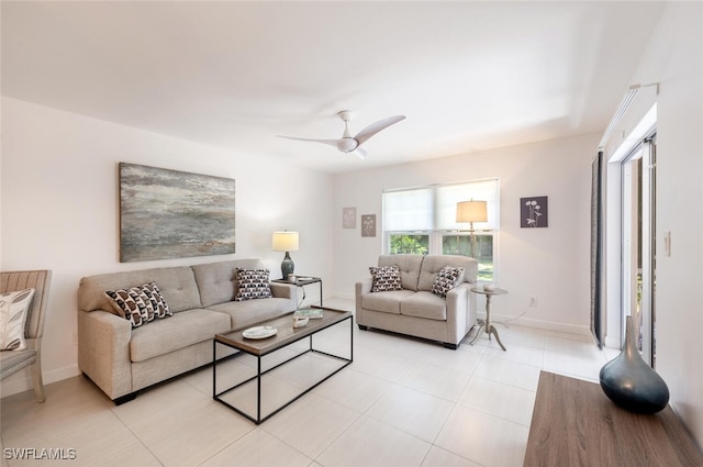 living area featuring ceiling fan, light tile patterned flooring, and baseboards