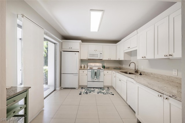 kitchen with light tile patterned floors, white appliances, a sink, white cabinetry, and light stone countertops