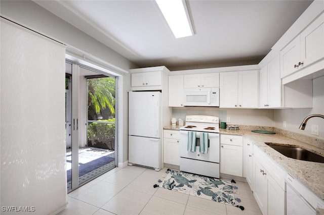 kitchen with light stone counters, white cabinets, a sink, light tile patterned flooring, and white appliances