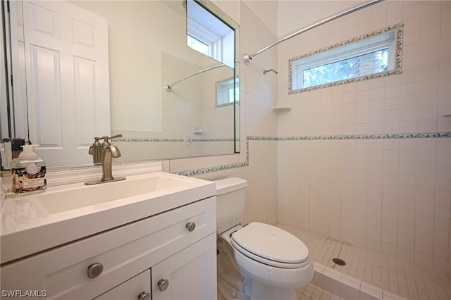 bathroom with tile walls, toilet, a healthy amount of sunlight, and large vanity