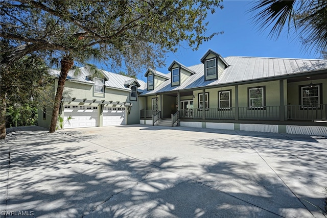 new england style home featuring covered porch and a garage