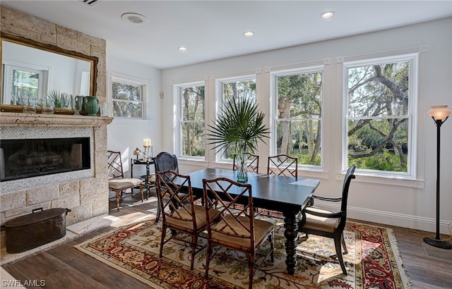 dining room with a tiled fireplace and dark hardwood / wood-style flooring