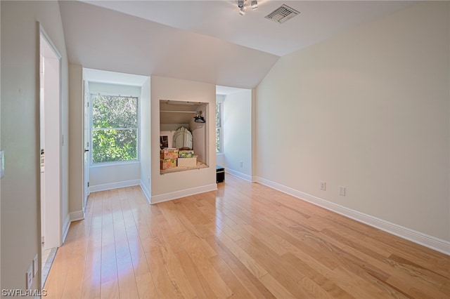 unfurnished bedroom featuring lofted ceiling and light hardwood / wood-style flooring