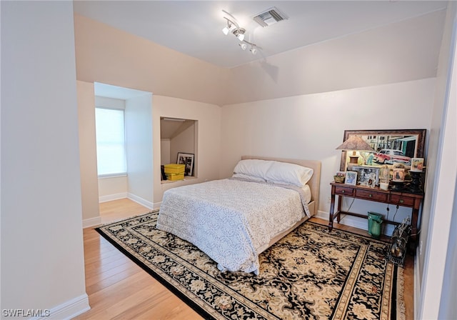 bedroom featuring light hardwood / wood-style flooring and rail lighting