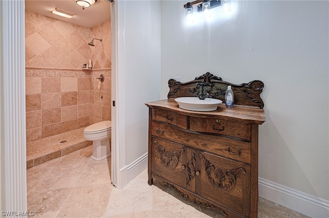 bathroom with toilet, tile floors, vanity, and tiled shower