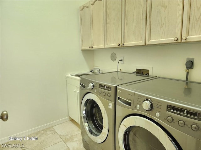 clothes washing area with light tile patterned floors, washing machine and dryer, sink, and cabinets