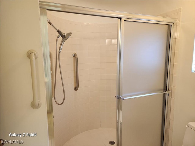 bathroom featuring toilet and a shower with shower door