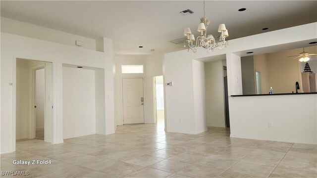 spare room featuring sink and ceiling fan with notable chandelier