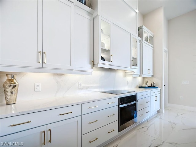 kitchen featuring black electric cooktop, decorative backsplash, oven, and white cabinets