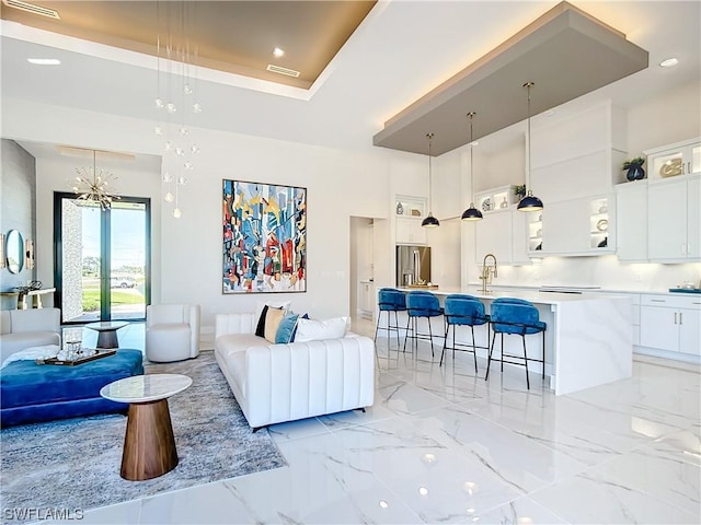 living room featuring sink, a tray ceiling, and a chandelier