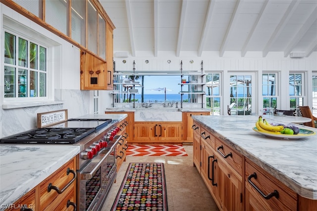 kitchen with light stone countertops, backsplash, beamed ceiling, stainless steel range, and tile flooring