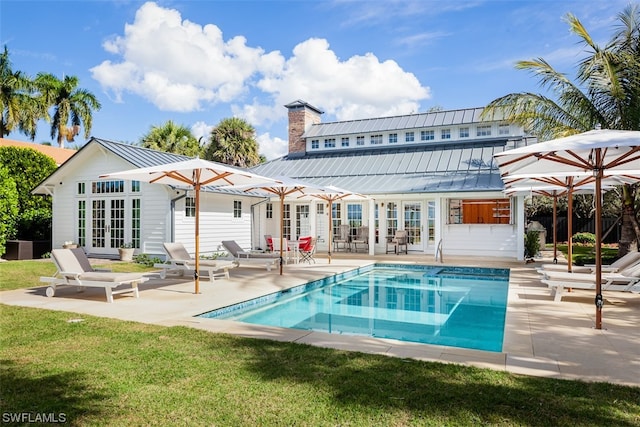 rear view of house featuring a lawn, french doors, and a patio