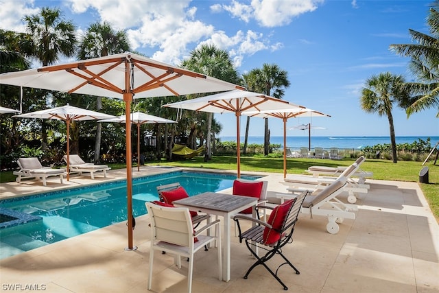 view of swimming pool with a lawn, a patio area, and a water view