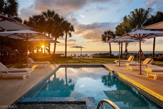 pool at dusk with a lawn and a patio