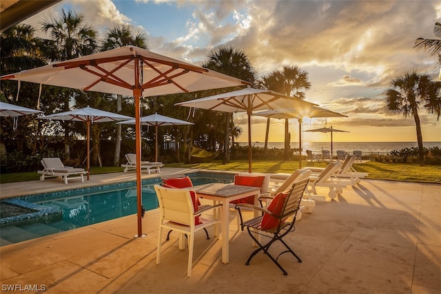 pool at dusk featuring a patio area