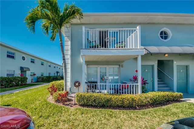 back of property with a yard and a balcony