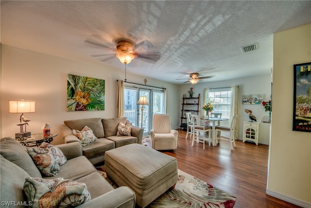 living room with dark wood-type flooring, a textured ceiling, and ceiling fan