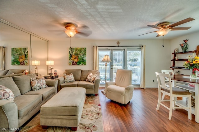 living room featuring light hardwood / wood-style floors, ceiling fan, and a textured ceiling