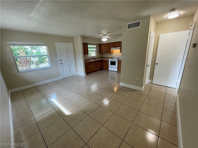 kitchen featuring light tile patterned flooring, white electric range oven, a textured ceiling, ceiling fan, and sink