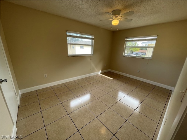 spare room with a textured ceiling, light tile patterned floors, and ceiling fan