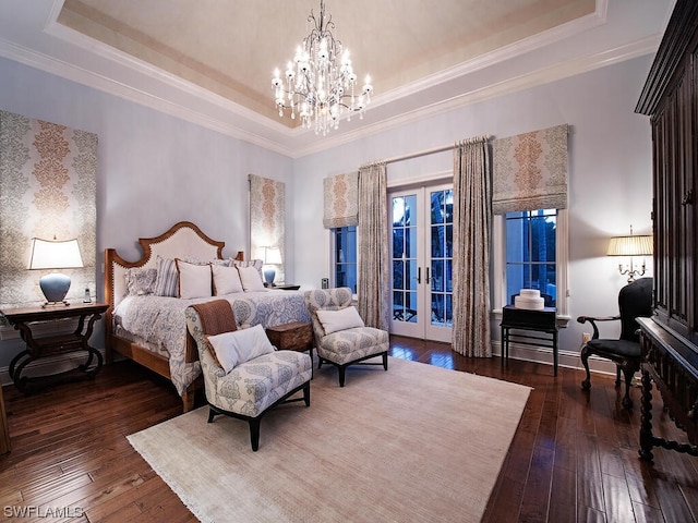 bedroom with dark hardwood / wood-style floors, a raised ceiling, french doors, and an inviting chandelier