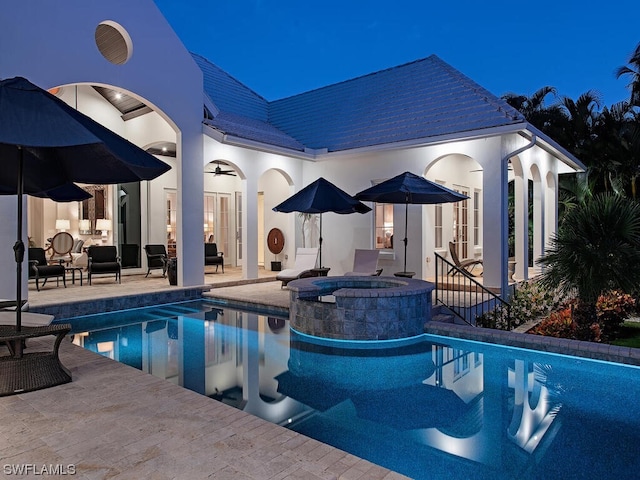 pool at twilight featuring a patio area and an in ground hot tub