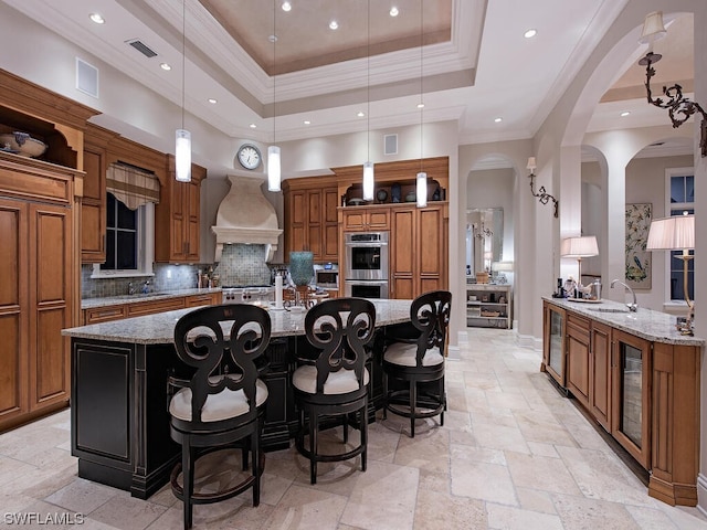 kitchen featuring hanging light fixtures, light stone countertops, and custom range hood