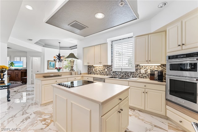 kitchen featuring a kitchen island, pendant lighting, sink, a tray ceiling, and cream cabinetry