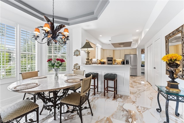 dining space featuring an inviting chandelier, a tray ceiling, and a wealth of natural light