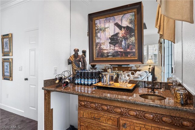 interior space with crown molding, sink, and dark stone countertops