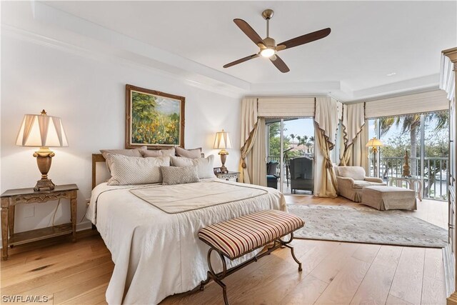 bedroom featuring multiple windows, access to outside, ceiling fan, and a tray ceiling