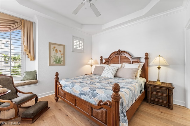 bedroom featuring crown molding, a raised ceiling, ceiling fan, and light wood-type flooring