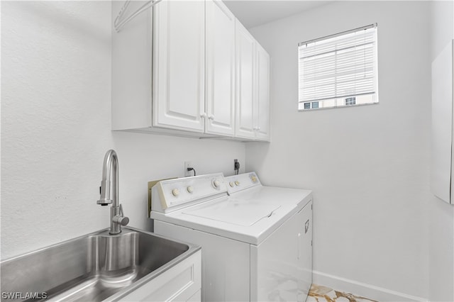 laundry room with cabinets, washing machine and clothes dryer, and sink