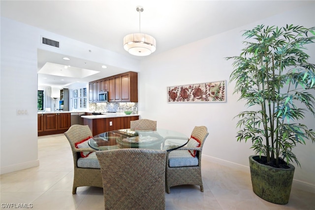 dining area featuring a raised ceiling and light tile flooring