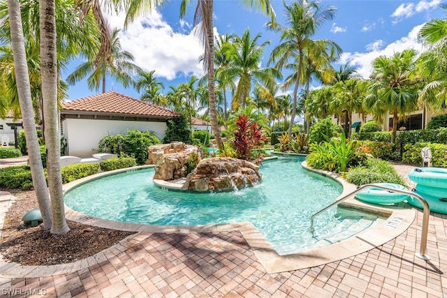 view of pool featuring a hot tub, pool water feature, and a patio area