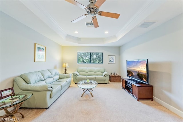 carpeted living room with a raised ceiling, ceiling fan, and crown molding