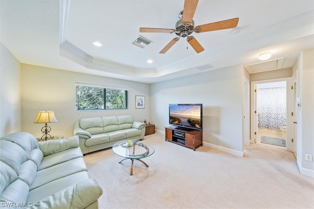 living room featuring ornamental molding, light colored carpet, ceiling fan, and a tray ceiling