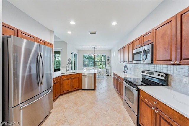 kitchen with hanging light fixtures, backsplash, sink, stainless steel appliances, and light tile floors