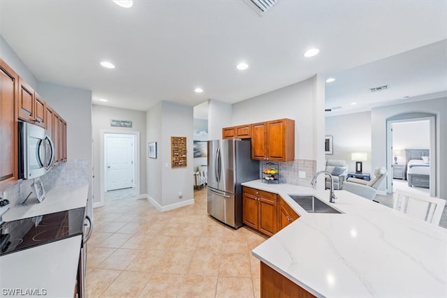 kitchen with stainless steel appliances, light tile floors, sink, backsplash, and light stone counters