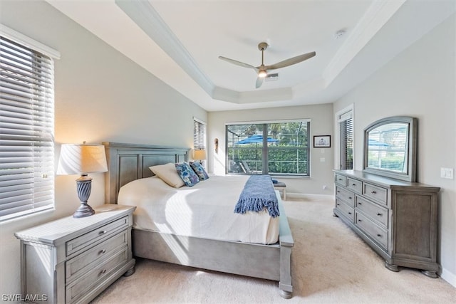 carpeted bedroom featuring ceiling fan and a raised ceiling