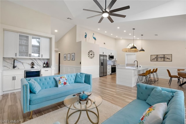 living room featuring beverage cooler, ceiling fan, sink, and light hardwood / wood-style flooring