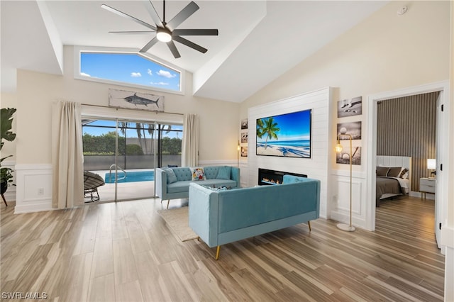 living room with high vaulted ceiling, ceiling fan, and light wood-type flooring