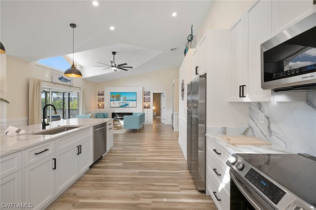 kitchen with vaulted ceiling, ceiling fan, light hardwood / wood-style flooring, appliances with stainless steel finishes, and white cabinets