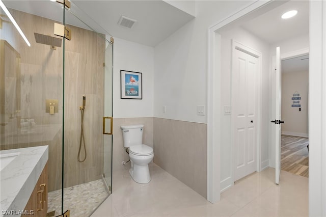 bathroom with vanity, a shower with door, tile flooring, and toilet